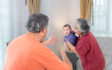 Obraz premium Grandparents and their little grandchild play happily in the living room of the house