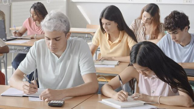 Group of diverse teenagers students taking an exam in a classroom. Education, students in class