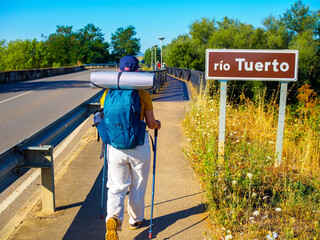 A pilgrim walking toward Rio Tuerto River in San Justo de la Vega, Spain.