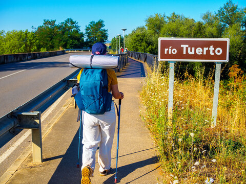 A pilgrim walking toward Rio Tuerto River in San Justo de la Vega, Spain.