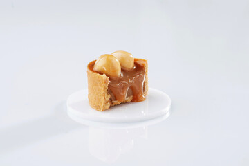 Single caramel tart with walnut against white background