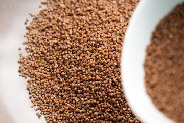 Preparation of dry buckwheat couscous. Nutritious raw ingredient in gray kitchen bowl and white cup for steaming close up