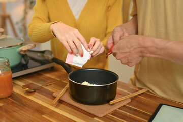 Cropped shot of young couple sharing a bowl of instant noodles enjoying a casual meal in kitchen
