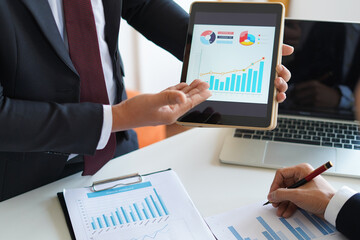 Businessman is showing or report about company profit and sale volume chart to supervisor or CEO in the meeting with smart device, business and financial concept