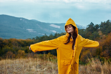 Serene Woman in Yellow Raincoat With Arms Outstretched Embracing the Beauty of Nature in the Field