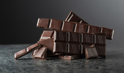 Broken bitter chocolate bar on a black background.