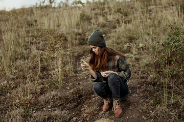 A stylish woman wearing a beanie and plaid shirt enjoying the breathtaking view from the hilltop during a leisure trip