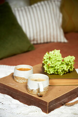 A serving tray with coffee cups and flowers stands on the bed in the bedroom