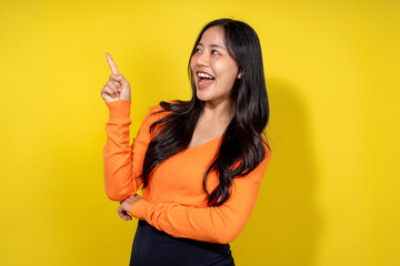 A woman in an orange shirt points to the sky