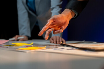 A man is pointing at a table with a yellow sticky note on it