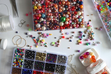Colorful beads, letter beads, threads and other jewelry making supplies on white background. Making...