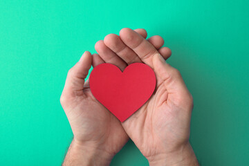 Fototapeta premium Healthy lifestyle with hand holding red heart on green background