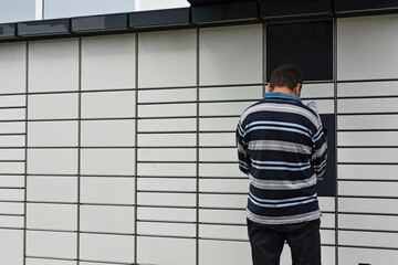 A man at a parcel locker receiving a parcel