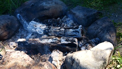 Obraz premium The glowing embers of a fire emit a light smoke as each ember slowly dies out. The close-up captures every detail of the glowing ember, making it ideal for projects requiring realistic ember effects.