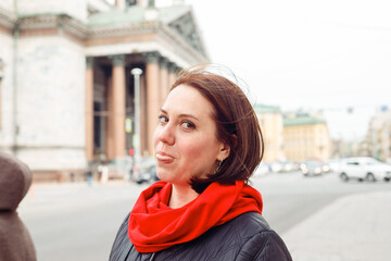 Fototapeta premium caucasian female woman playfully sticks out tongue on street of european historical city. date, flirt, love. female portrait