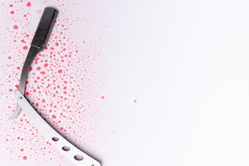 A detailed top view of a bloodied barber's razor against a white backdrop