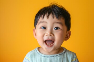 A cheerful toddler beams with delight, showcasing his bright smile in front of a lively yellow backdrop, capturing pure joy. Generative AI