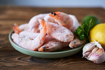 Frozen shrimp with lemon and parsley on a wooden table