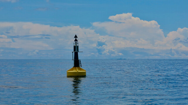 Weather buoy on the surface of a calm sea. Weather buoy in the open ocean on a cloudy day.