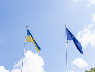 Ukrainian and European union flags waiving against blue sky 