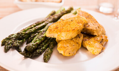 Fried chicken breast pieces with asparagus on white plate