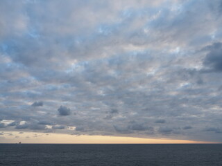 Vista del amanecer desde el acantilado con el cielo lleno de nubes y el horizonte del mar rojizo por el sol
