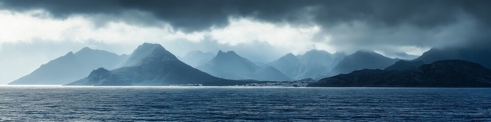 A beautiful view of the ocean with mountains in the background. The sky is cloudy and the water is calm