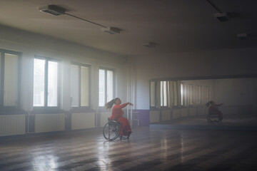 Woman in an elegant red dress dancing in a wheelchair, making graceful movements. Para dance sport concept.