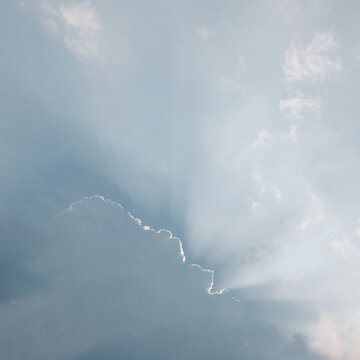 Abstract background. Clouds in the pale blue sky covering the sun. Silver lining. Concepts of optimism and hope.