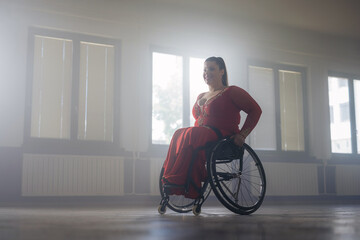 Smiling confident young woman enjoying performing wheelchair dance in a ballroom. Inclusive dancing and disability concept.