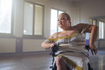 Woman practicing and performing a freestyle wheelchair dance at a dancing studio, wide shot. Para dance sport concept.