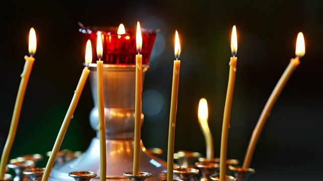 Burning church candles on candlesticks with a lamp in the church. The concept of faith in God and observance of church traditions and rules.