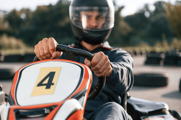 Front view, driving. Man is outdoors, kart racing conception