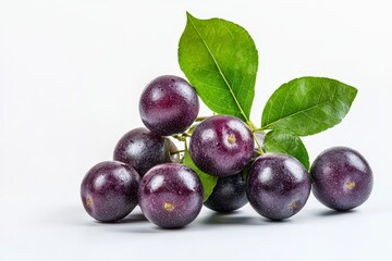 Fototapeta premium A cluster of dark purple fruits with green leaves on a light background.