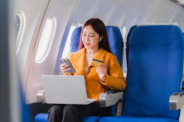 In-Flight Purchases: Young Asian woman using laptop and credit card for online shopping during flight 