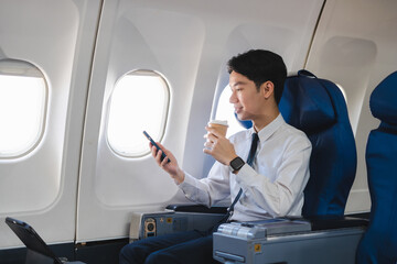 Traveling and technology. happy young businessman working on laptop computer and smartphone while sitting in airplane.