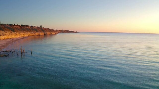 Aerial view of beautiful cliffs and serene beach at sunset over the ocean, Port Willunga, Australia.