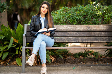 Young woman using a digital tablet sitting on a bench in a park