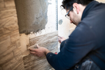 Closeup of a tiler applying tiles to a wall
