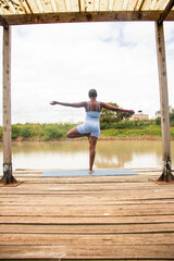 A beautiful young black woman practicing yoga outdoors in the countryside