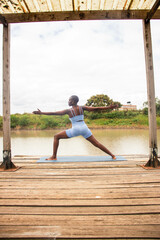 A beautiful young black woman practicing yoga outdoors in the countryside
