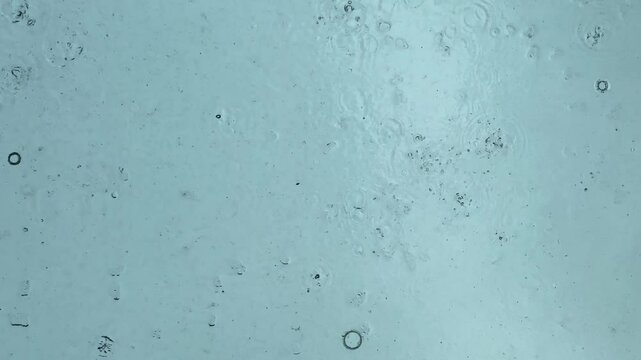 Abstract vertical background from raindrops view from under the mirrored ceiling against the raindrop direction from sky,  low light natural while raining.