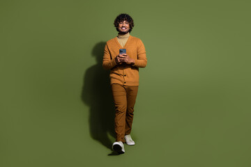 Full body photo of attractive young man walk hold telephone dressed stylish brown clothes isolated...