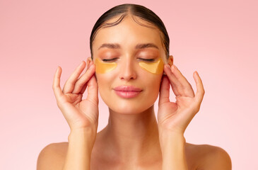 Lovely lady applying golden gel eye patches under eyes, caring for the skin around eyes, prevents...