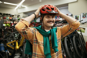 Portrait of happy smiling man cyclist wearing safety helmet at sport shop