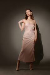 Fototapeta premium Serie of studio photos of female model in elegant beige strapless maxi dress
