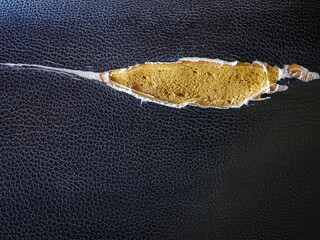 A leather motorcycle seat that was torn to reveal the foam inside.