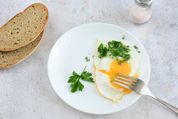 a plate of fried eggs with parsley and some slices of bread flat lay