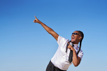 A man in a white shirt and black tie is singing and pointing to the sky