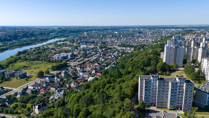 Drone photography of a city surrounded by nature and river during summer day